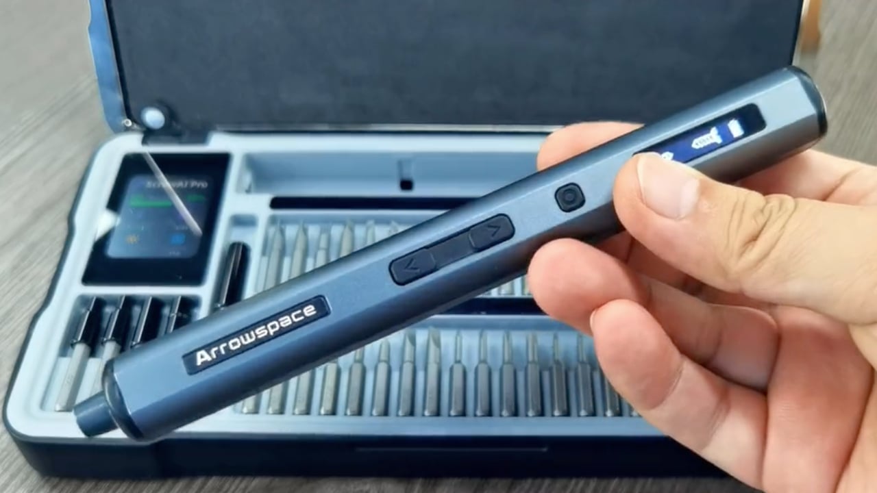 Arrowspace S1 precision driver held in a hand above its open case of bits, with the case's small screen visible